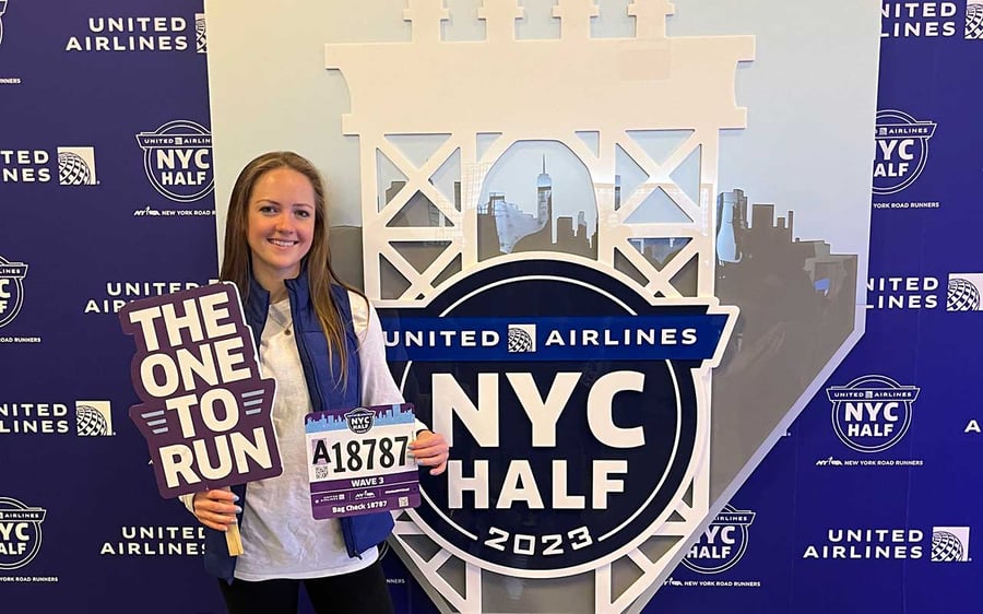 Tessa-in-front-of-medal-wall-w-bib-and-sign