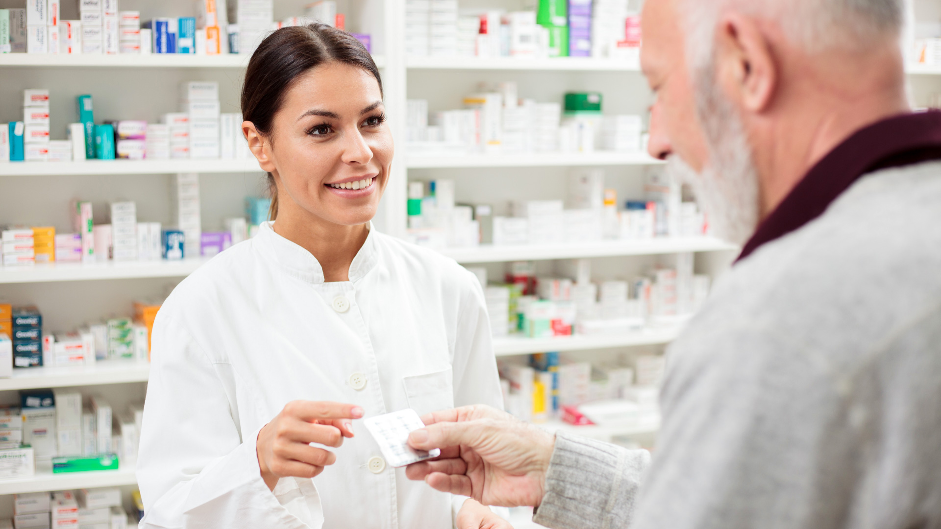 Senior happy patient picking up prescription at a pharmacy