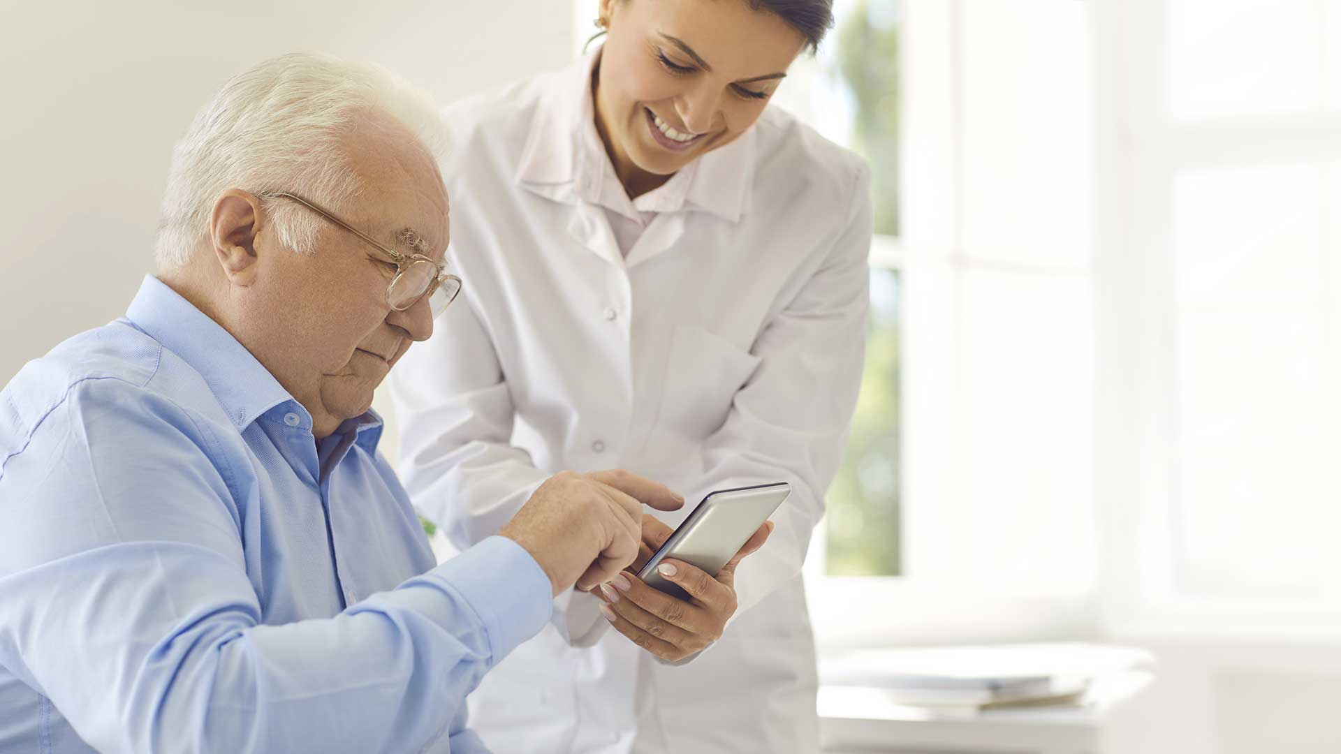 healthcare provider helping elder patient to use technology
